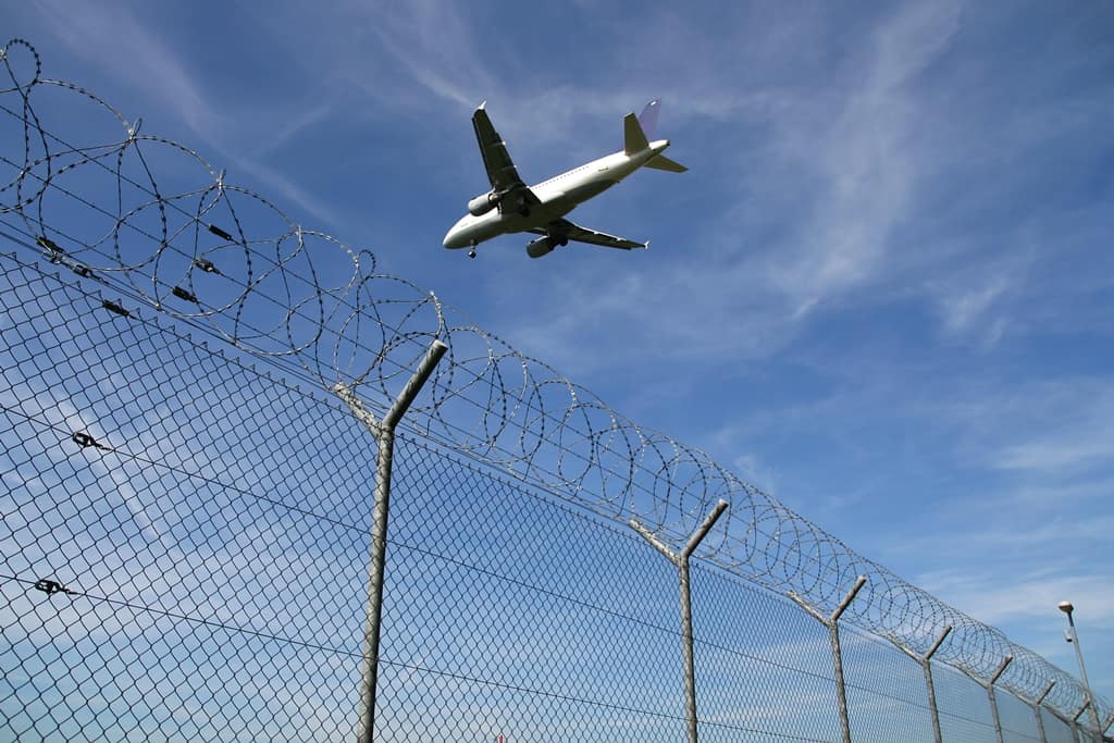 Aircraft flying above chain-link fence